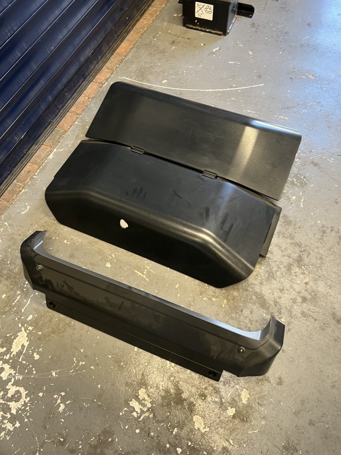 Removed cover panels laid out on the workshop floor.
